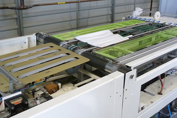 La plieuse draps blanc de la blanchisserie des Lavandières d'Aquitaine